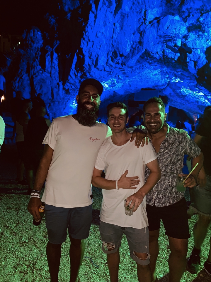 Groupe de trois hommes posant dans un décor de grotte faiblement éclairée.
