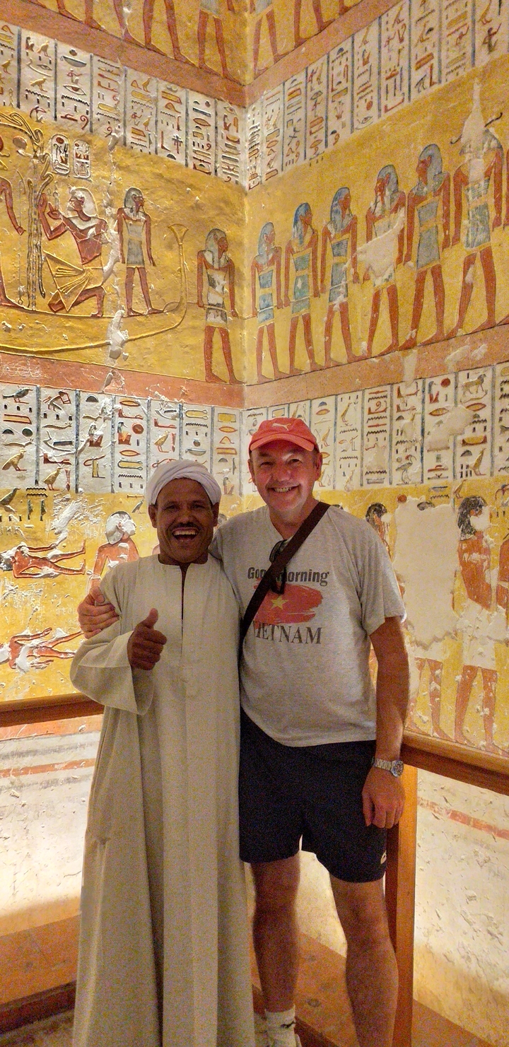 Two people posing in front of a wall with Egyptian hieroglyphs.