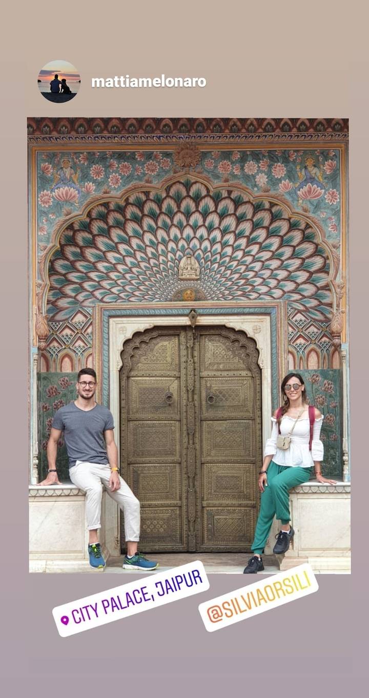 Deux personnes debout à côté d'une porte historique colorée et ornée.