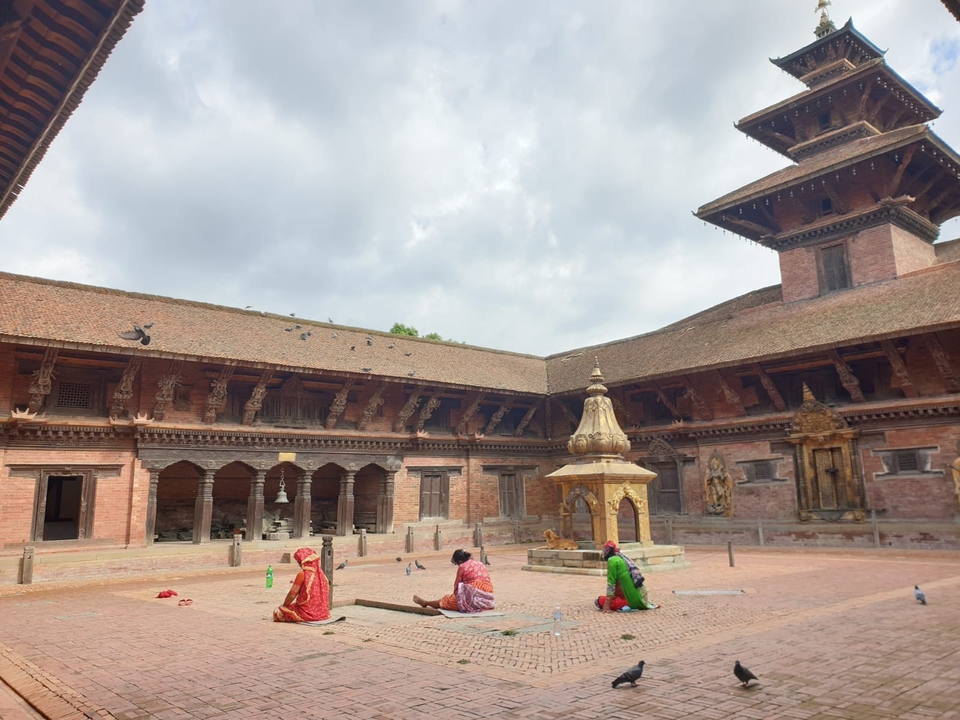 Des gens assis dans une cour historique entourée d'architecture en briques.