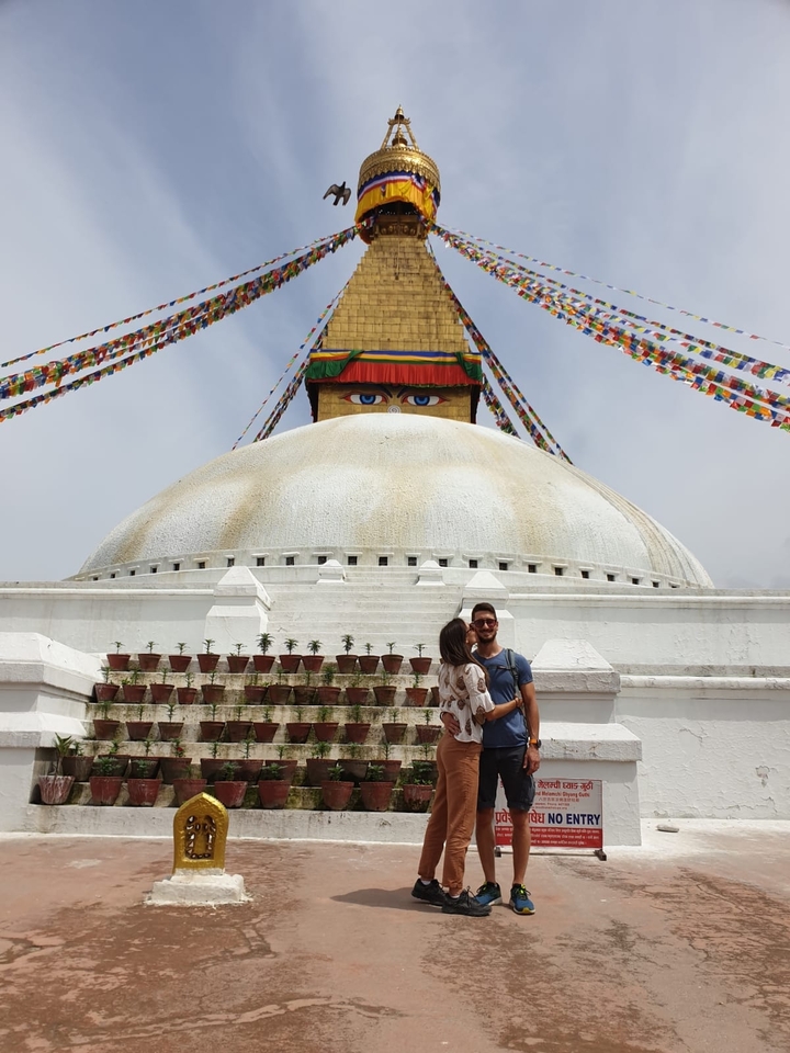 Stupa avec des drapeaux de prière colorés et un couple au premier plan.