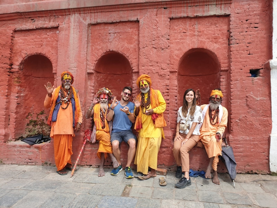Un groupe de personnes, incluant des sadhous, contre un mur rouge.
