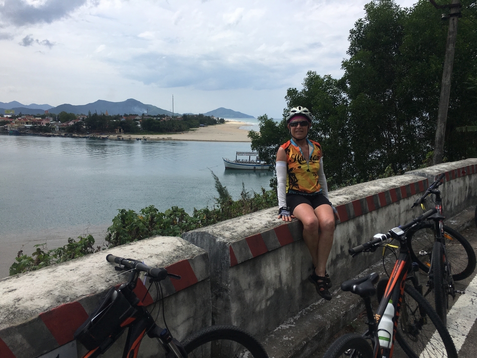 Cycliste se reposant sur une barrière surplombant une rivière.