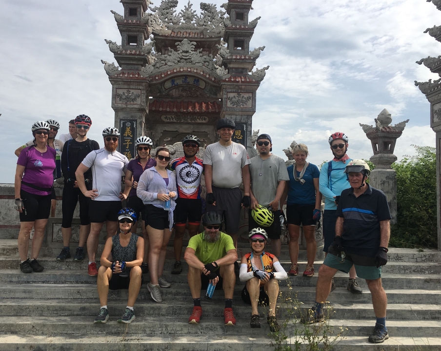 Groupe de cyclistes posant devant une entrée ornée.