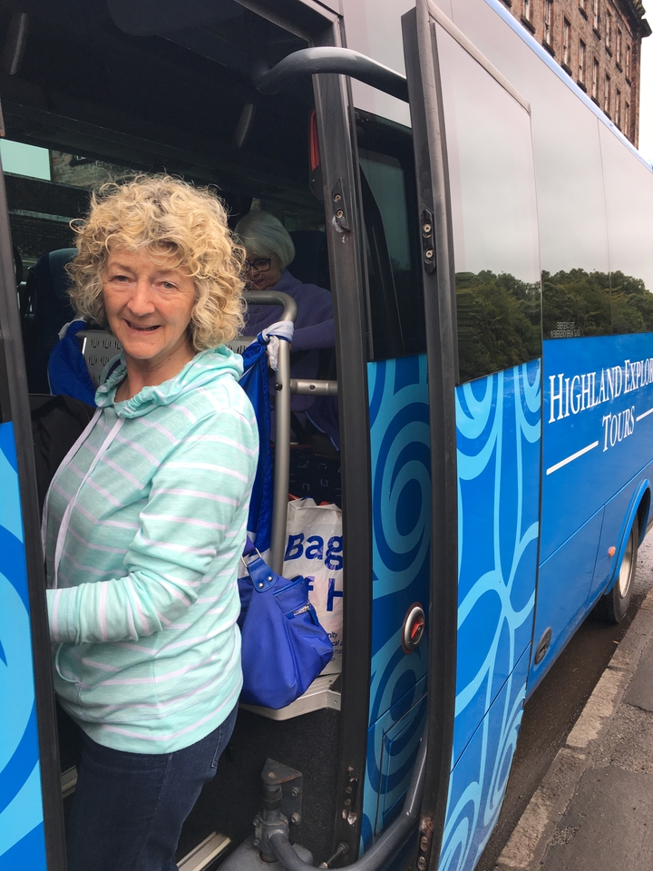 Femme montant dans un autocar touristique dans une région pittoresque.