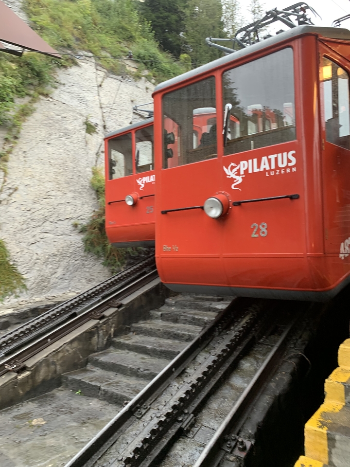 Trains à crémaillère rouges sur des voies escarpées avec un arrière-plan rocheux.