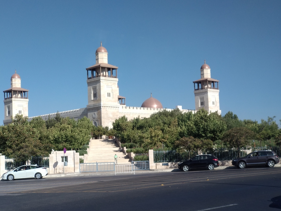 Mosquée avec dômes et minarets entourée d'arbres et de voitures.