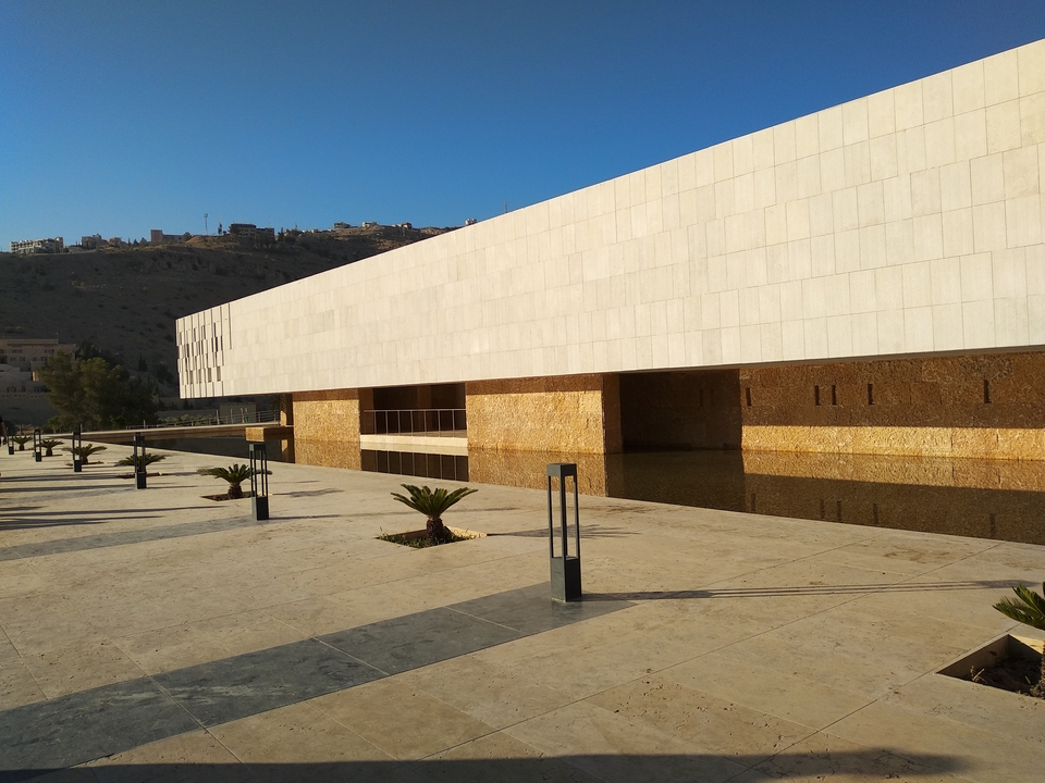 Bâtiment architectural moderne avec des éléments aquatiques reflétant la lumière du soleil.