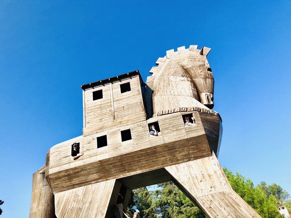 Grande structure de cheval de Troie en bois avec des personnes à l'intérieur.