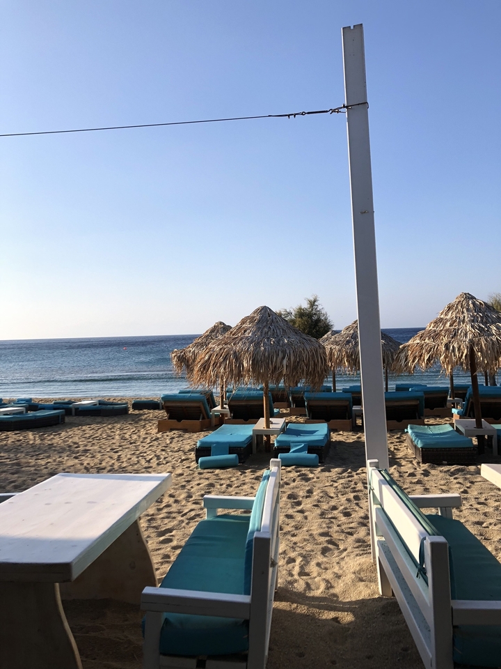 Scène de plage avec parasols en paille et transats turquoise.