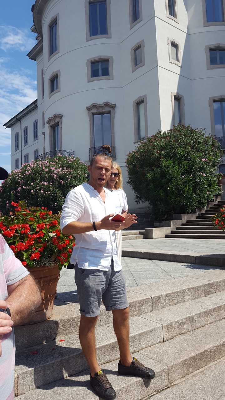 Un couple debout à l'extérieur devant un bâtiment et des fleurs.