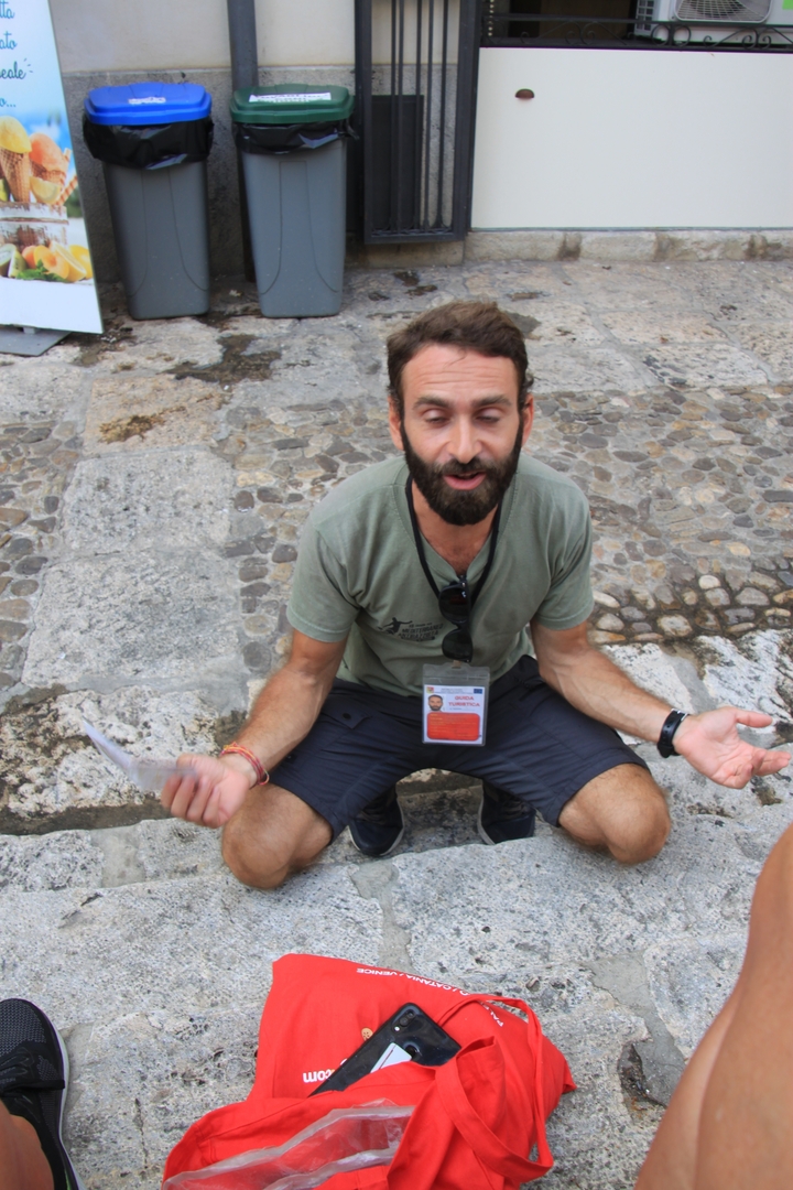 Homme assis dans une rue pavée tenant des cartes.