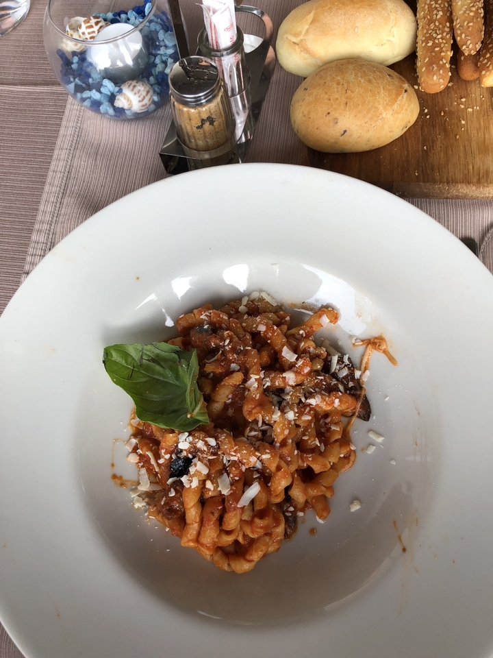 Plat de pâtes avec sauce tomate et fromage parmesan dans un bol blanc.