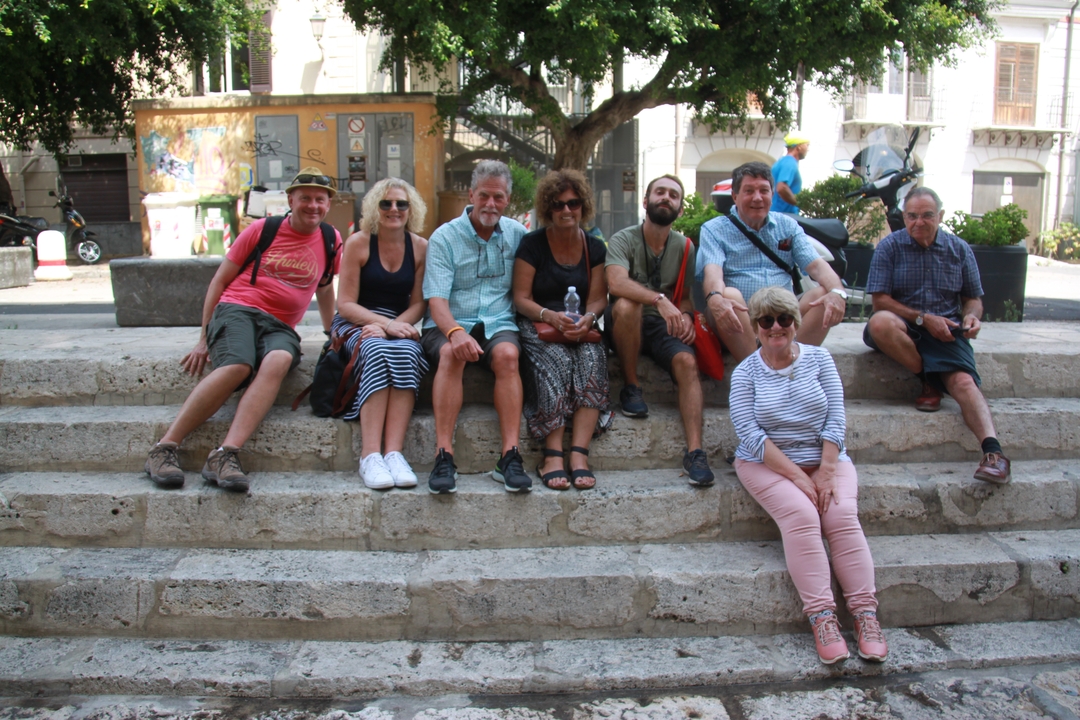 Groupe de personnes assises sur des marches dans un cadre extérieur.