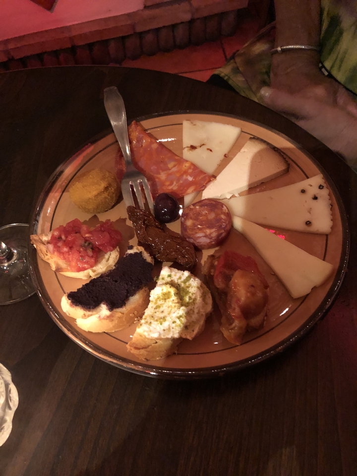 Assortiment d'amuse-gueules comprenant fromage, charcuterie et pain.