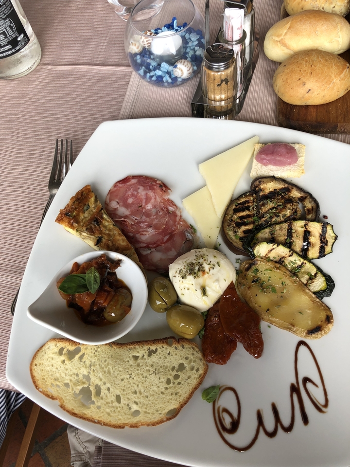 Assiette avec divers antipasti comprenant du fromage, de la charcuterie et des légumes.