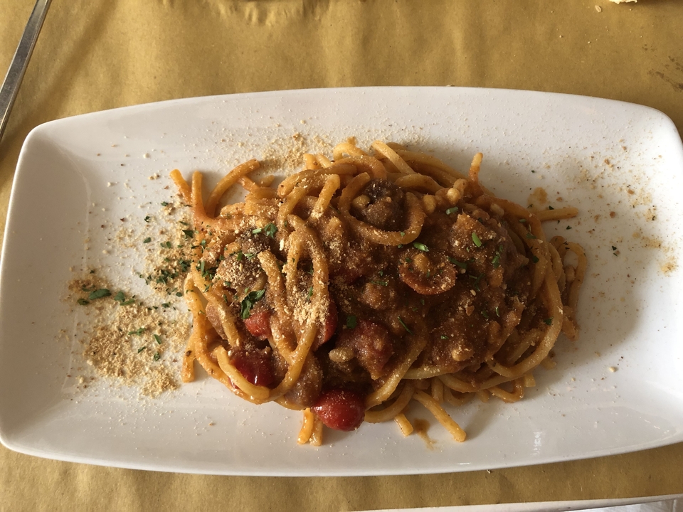 Assiette de pâtes avec sauce et herbes saupoudrées sur une table.