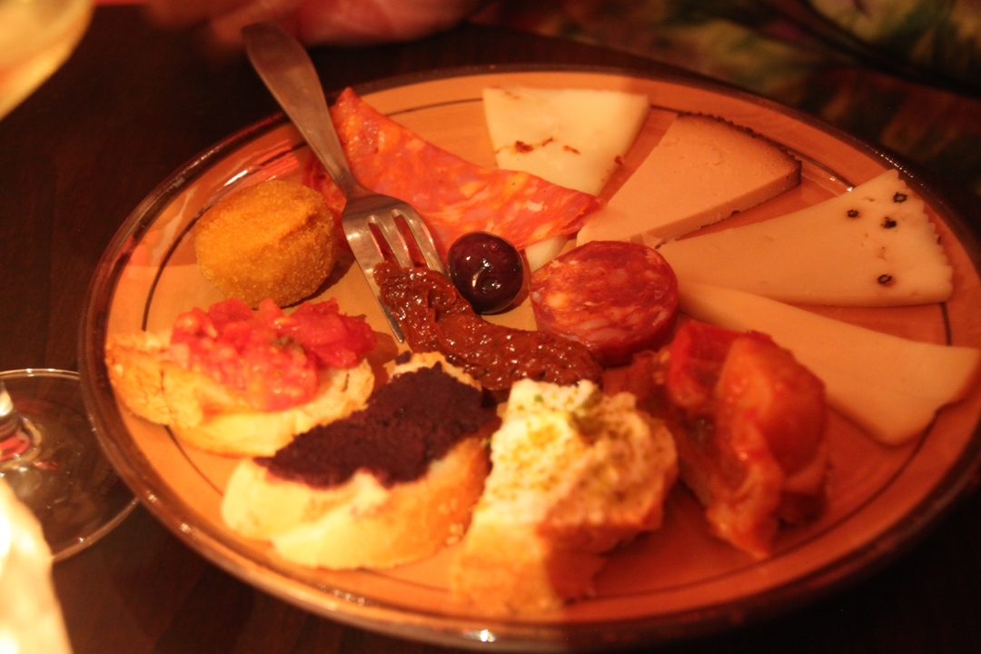 Assiette d'amuse-bouches italiens variés avec fromages et charcuteries.