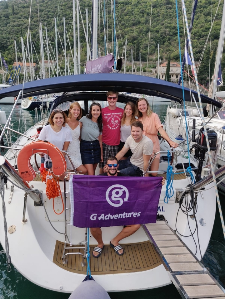 Groupe d'amis posant sur un bateau avec un drapeau G Adventures.