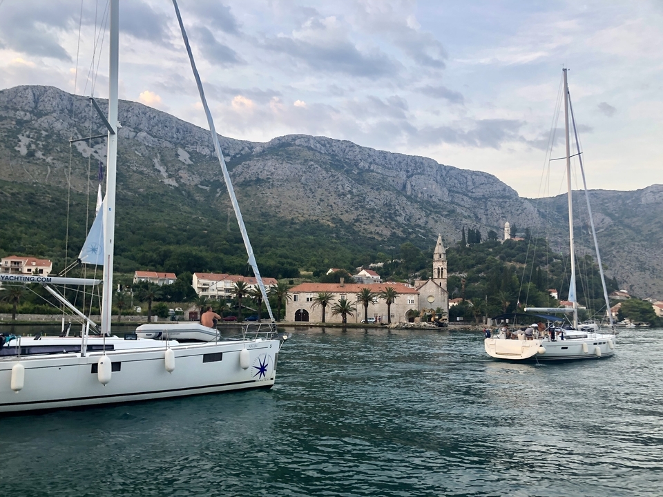 Bateaux ancrés dans une baie paisible avec un paysage vallonné.