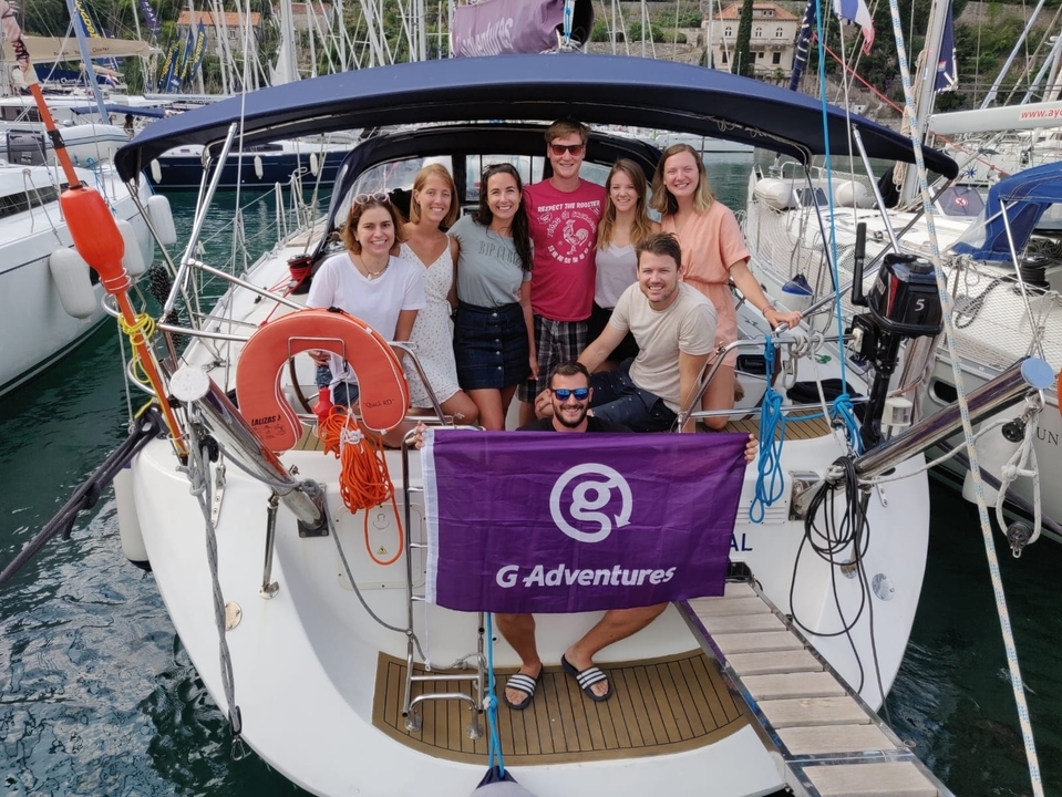 Groupe d'amis posant sur un yacht avec un drapeau G Adventures.