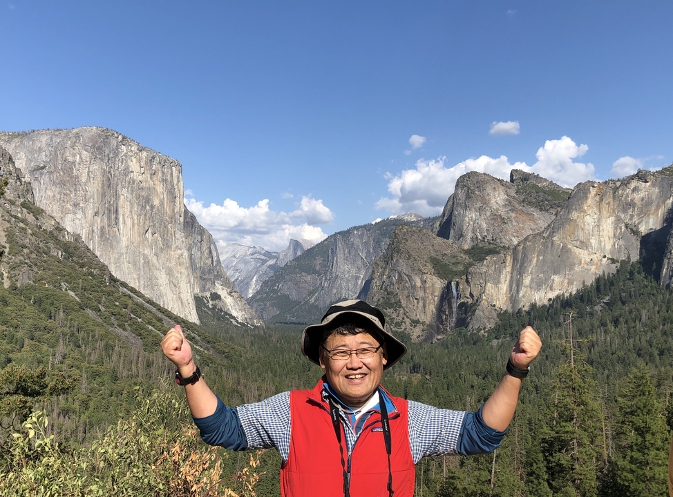 Homme avec les bras levés devant le paysage de Yosemite.