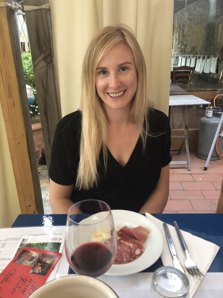 Femme assise à une table en plein air avec un verre de boisson.