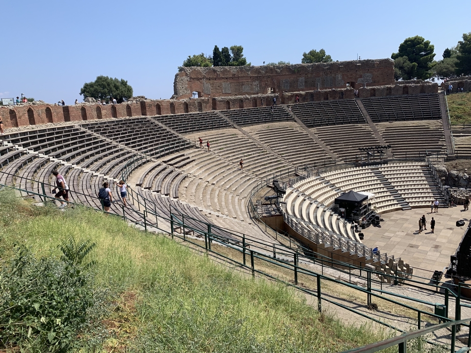 Théâtre romain antique avec gradins en pierre et touristes en visite.