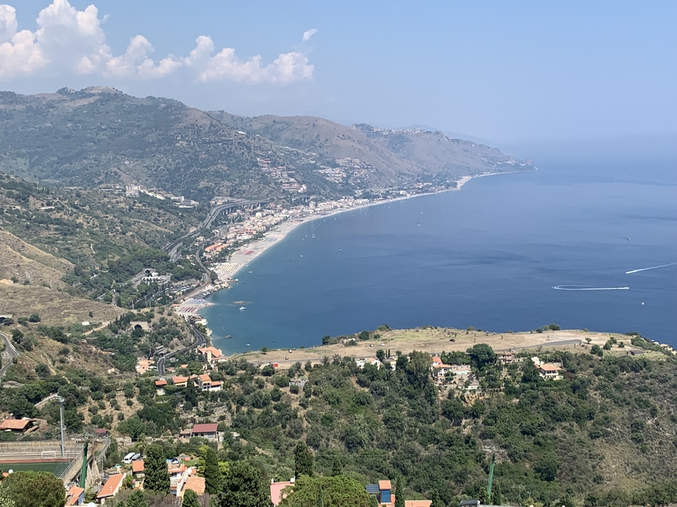 Vue aérienne d'une ville côtière avec la mer et les collines.
