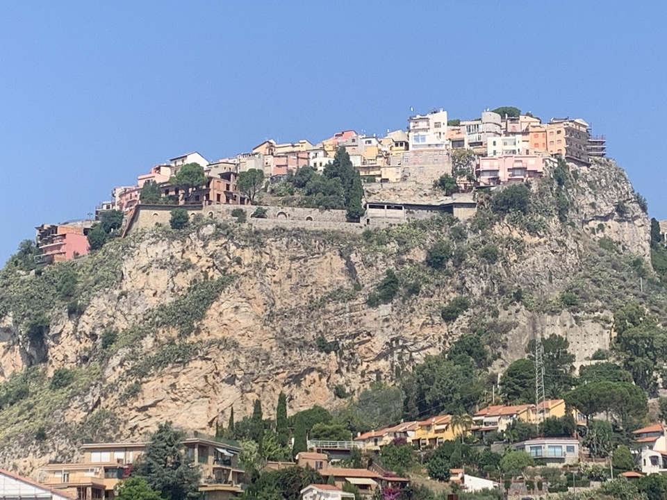 Ville perchée avec des bâtiments colorés sur une colline rocheuse.
