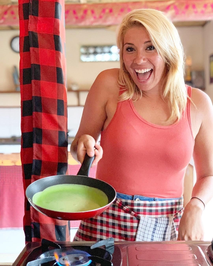 Woman excitedly cooking in a kitchen with a frying pan.
