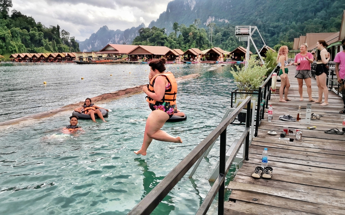Person jumping into a lake off a dock at a resort.