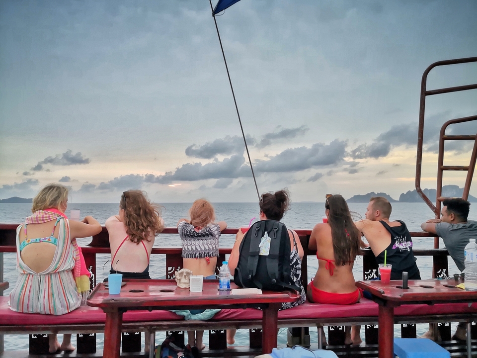 Group of people on a boat enjoying a sunset over the ocean.