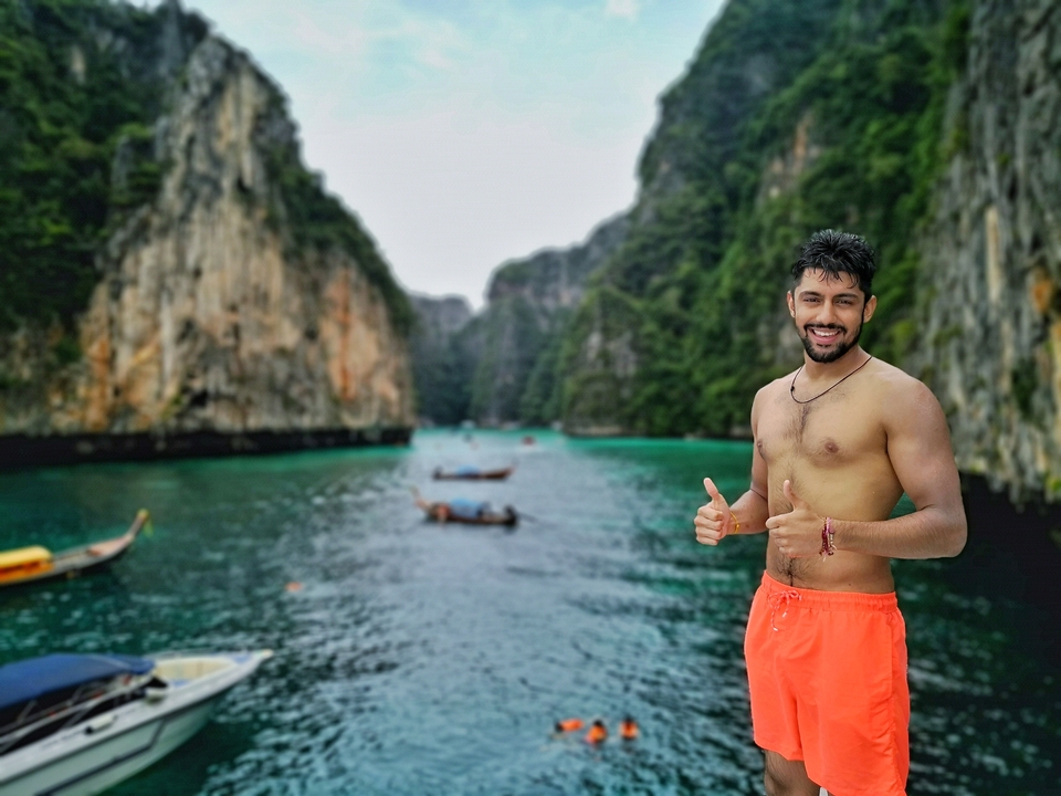 Man posing in front of dramatic cliffs by the sea.