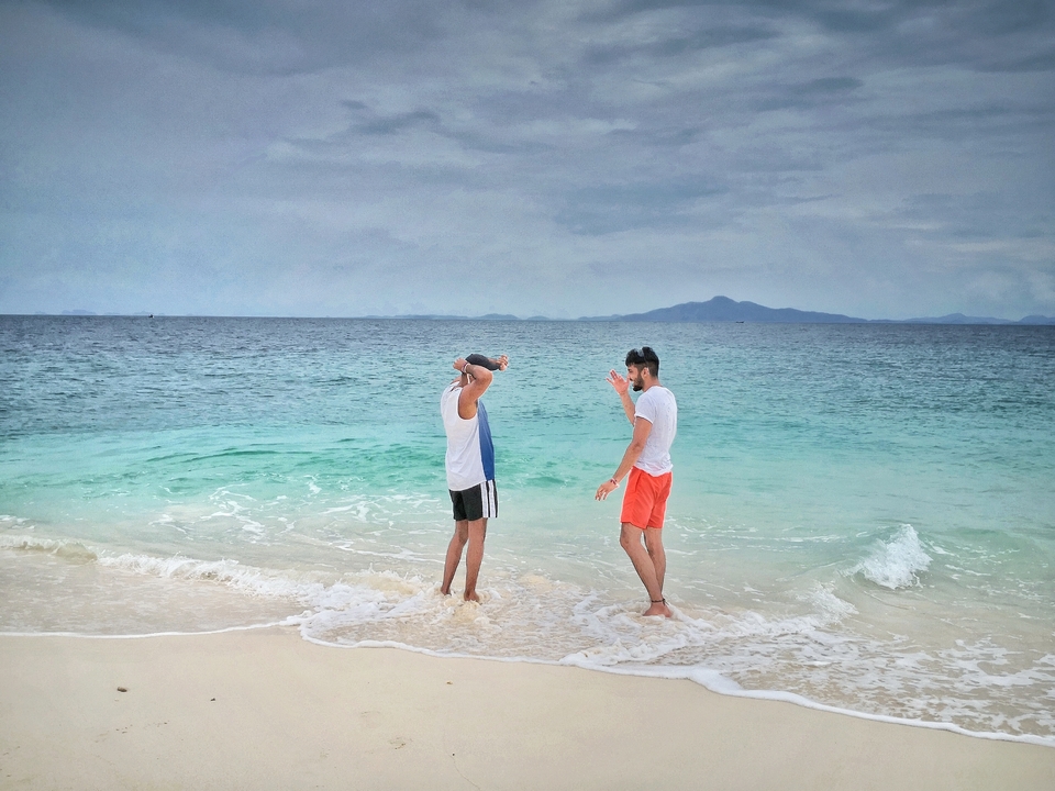 Two men standing in the surf on a beach.