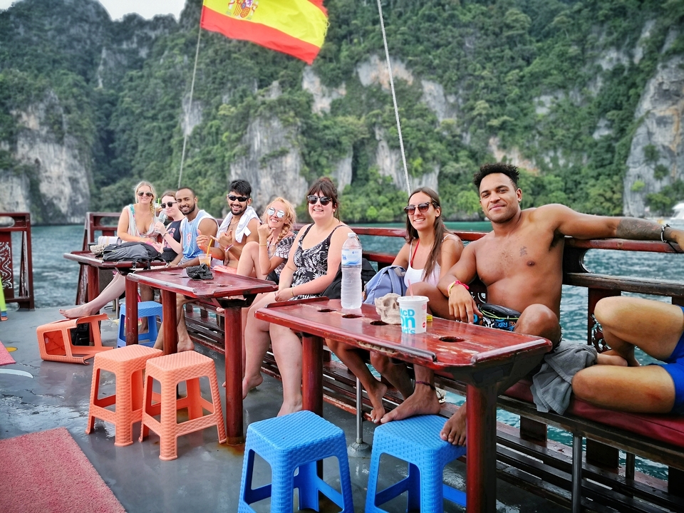 Group sitting on a boat with scenic cliffs in the background.