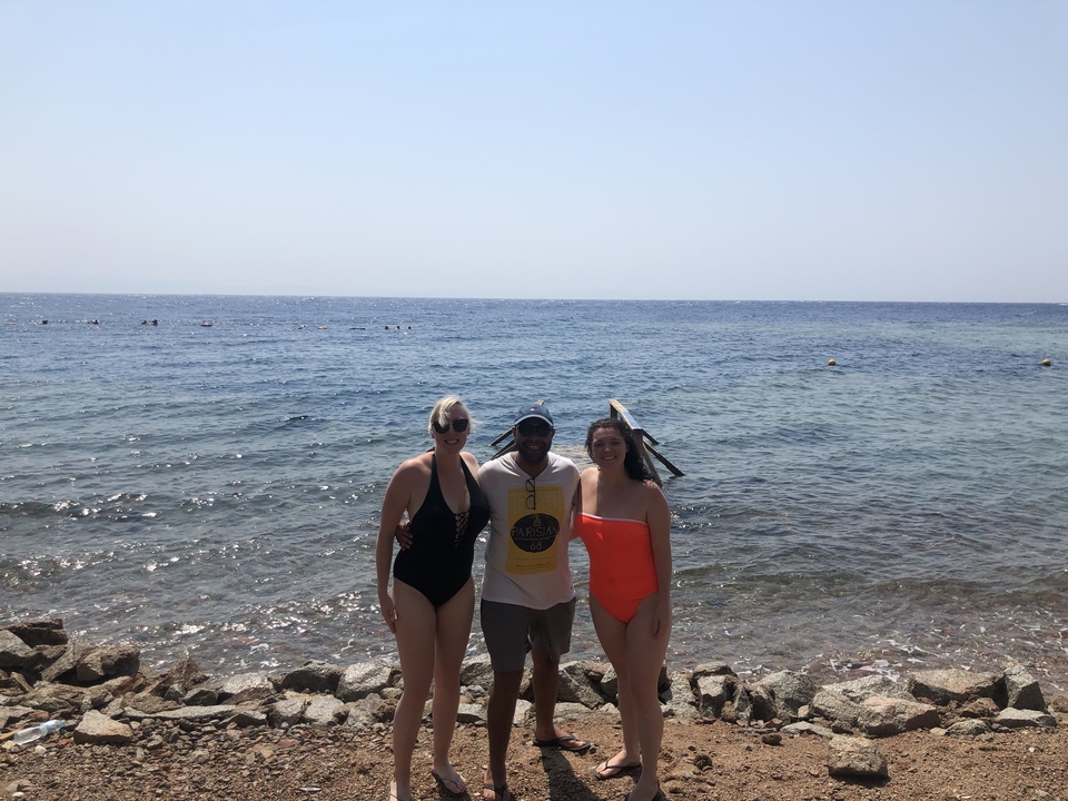 Trois personnes en maillot de bain posant près de la mer.