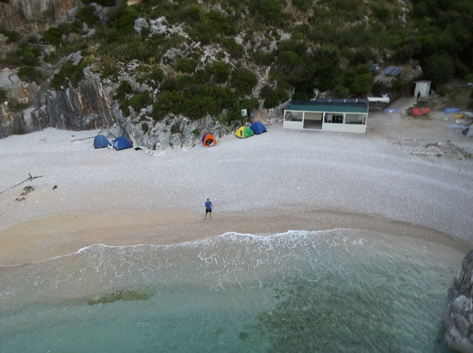 Une plage avec des tentes et une seule personne debout sur le sable.