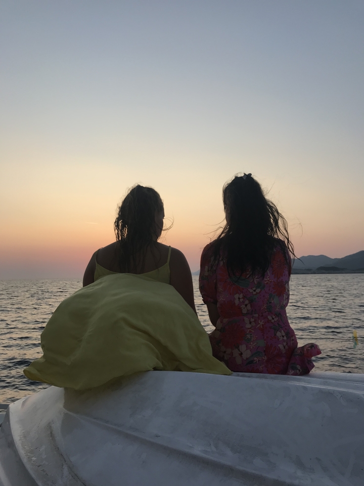 Deux personnes assises face à la mer au coucher du soleil.
