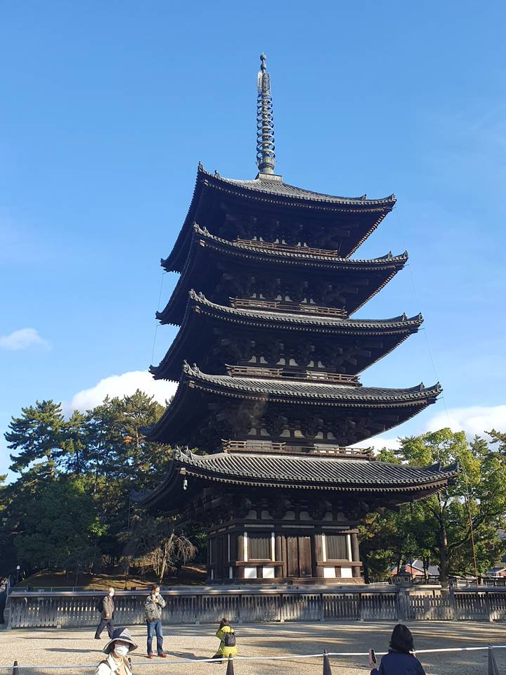 Pagode japonaise traditionnelle avec des gens qui marchent en dessous sous un ciel lumineux.