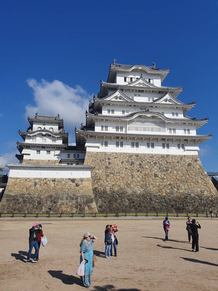 Château d'Himeji avec des touristes qui marchent devant par une journée ensoleillée.