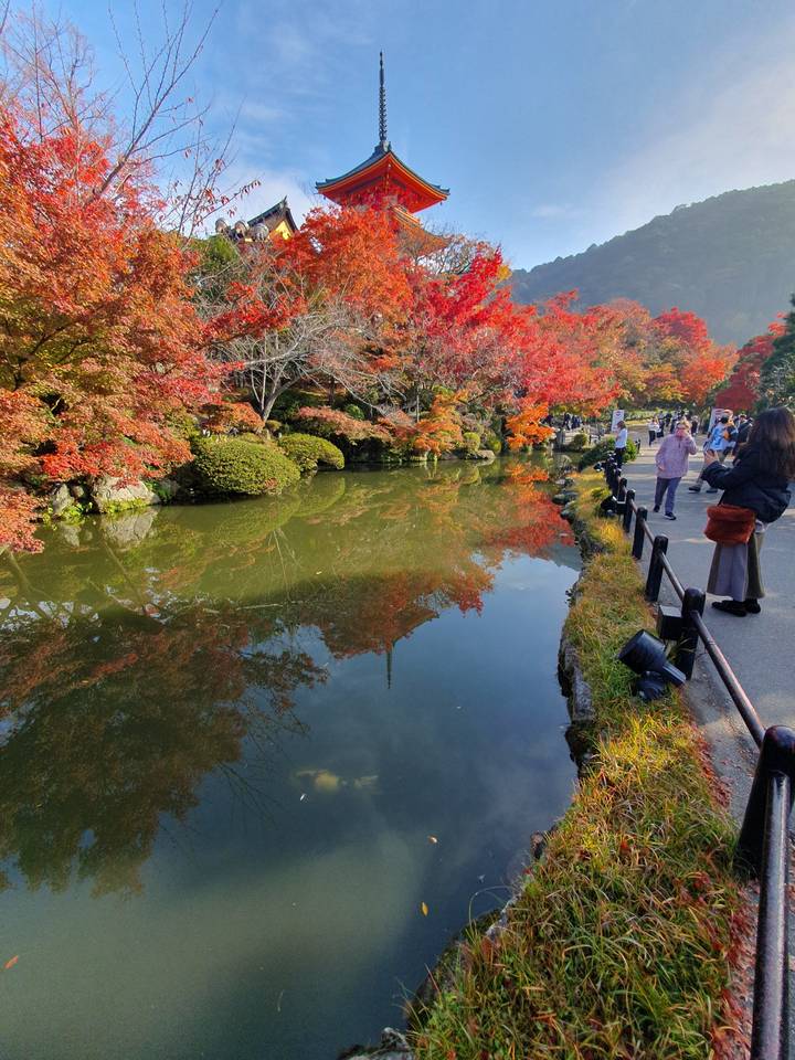 Pagode et feuillage d'automne reflétés dans un étang serein.