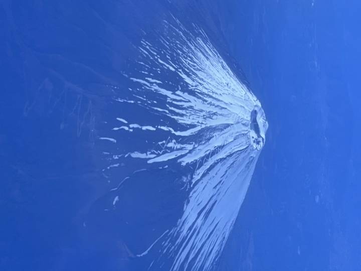 Pic volcanique enneigé sur fond bleu.