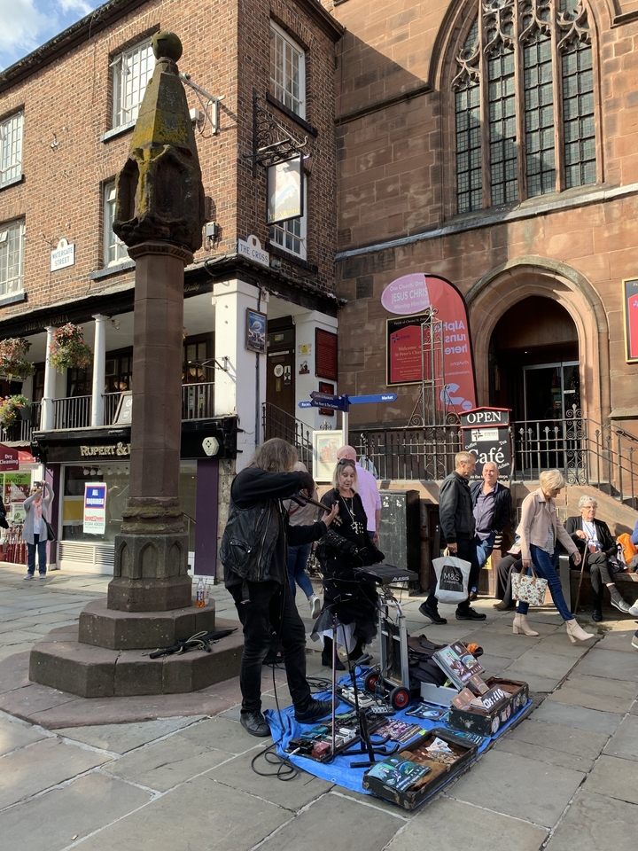 Musiciens de rue et personnes dans un cadre urbain avec une architecture historique.
