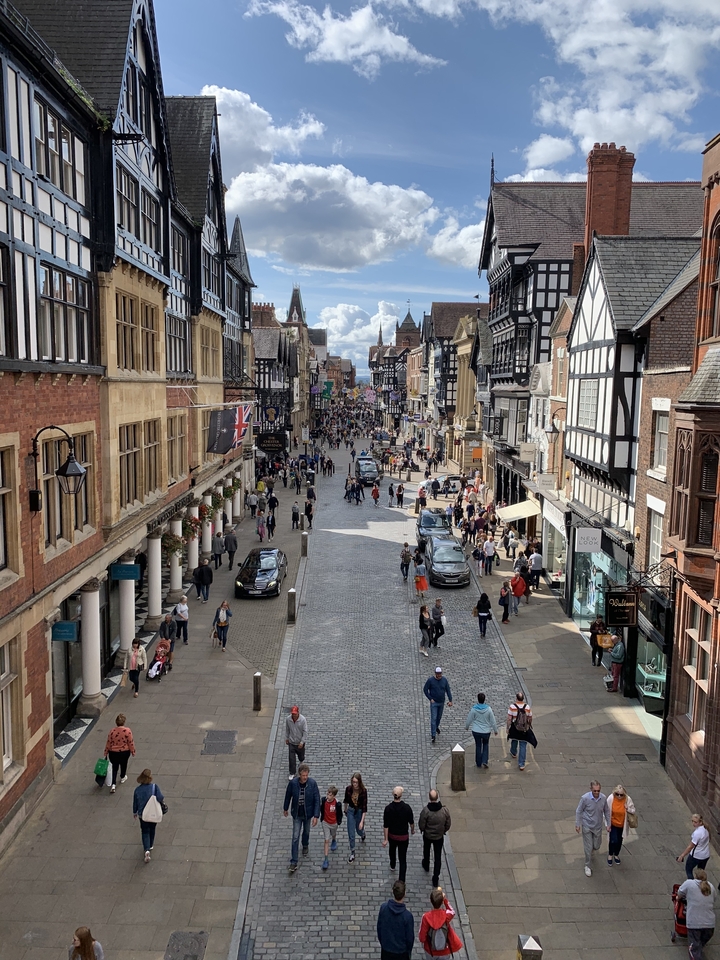 Scène de rue animée avec des bâtiments historiques à colombages et des gens.