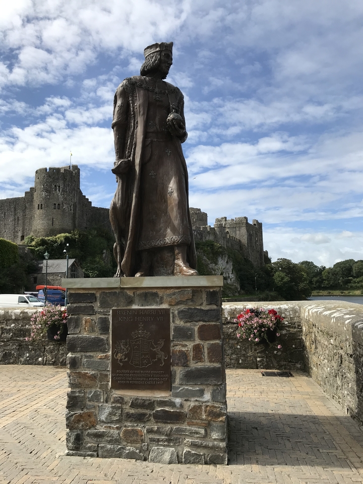 Une statue du roi Henri VI avec un château en arrière-plan.