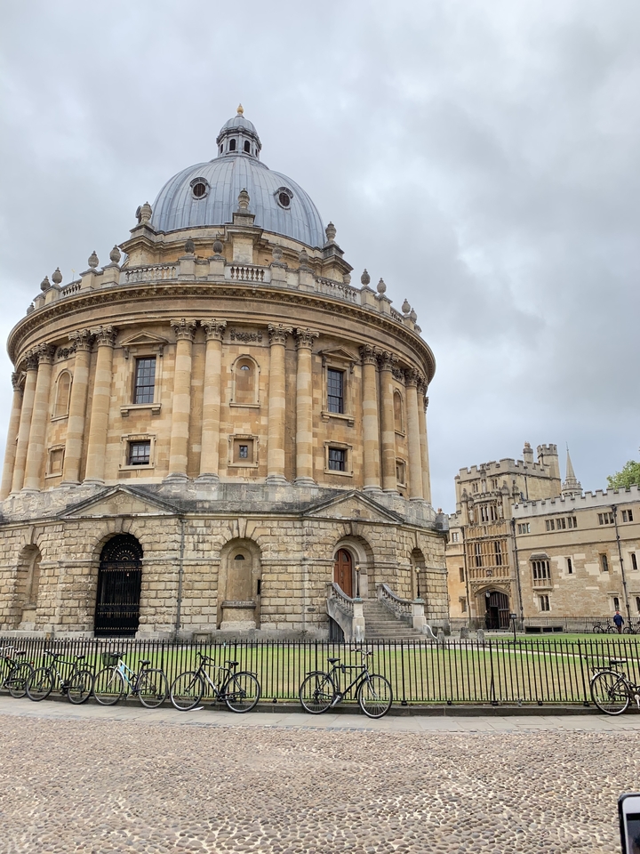 Bâtiment rond historique avec des décorations ornées sous un ciel nuageux.