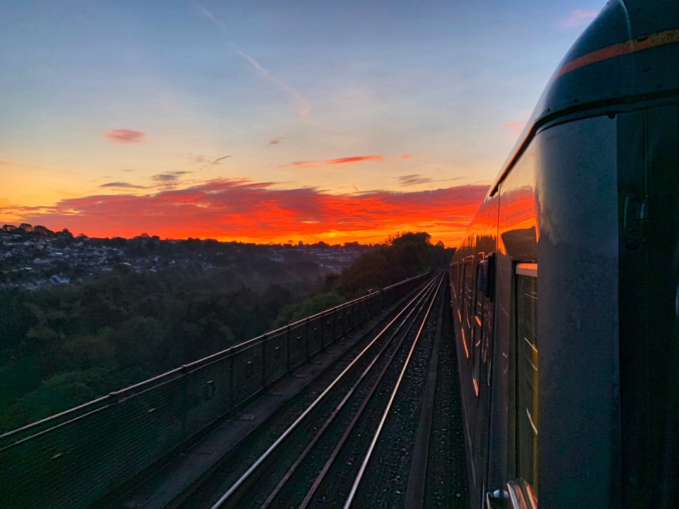Un train traversant un paysage pittoresque au coucher du soleil.