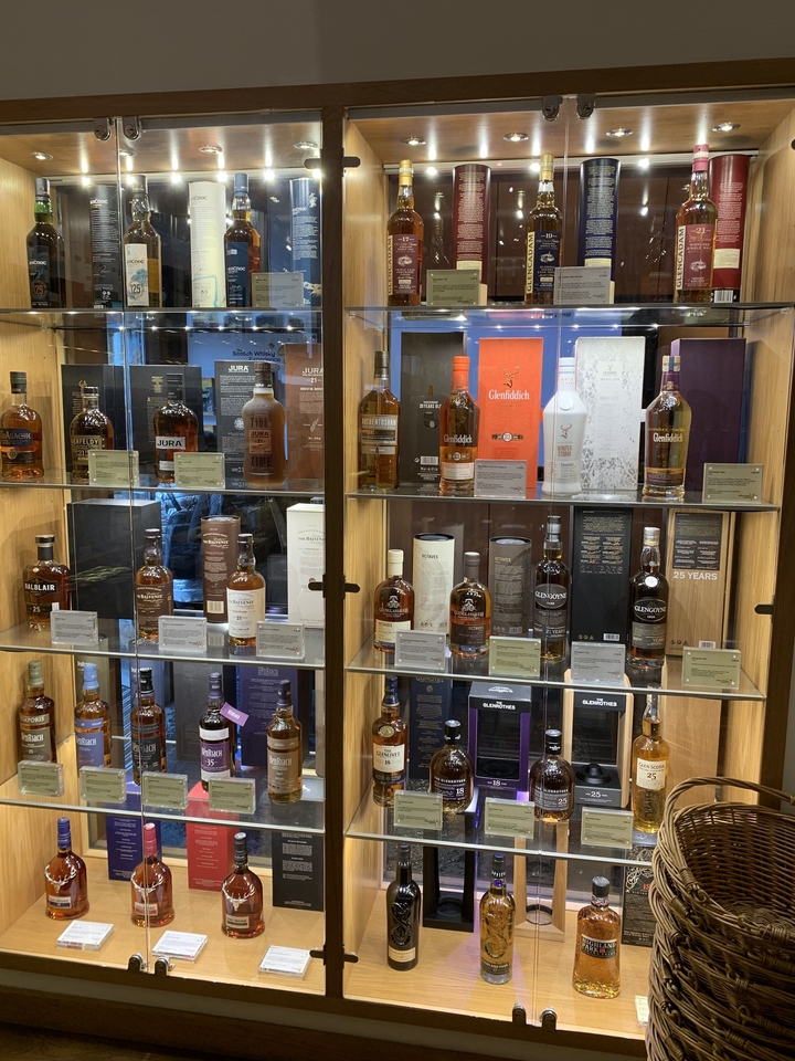 Présentation de diverses bouteilles de whisky dans un magasin.
