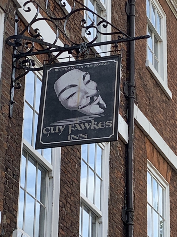 Une enseigne de pub affichant un masque avec le texte « Guy Fawkes Inn ».